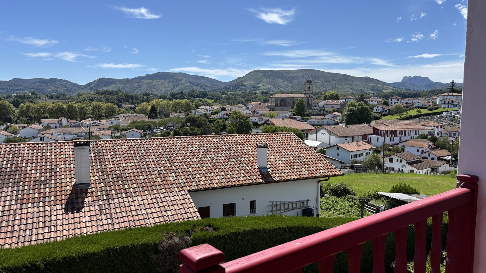 Balcon à garde-corps rouge avec vue sur les toits et les montagnes du Pays basque