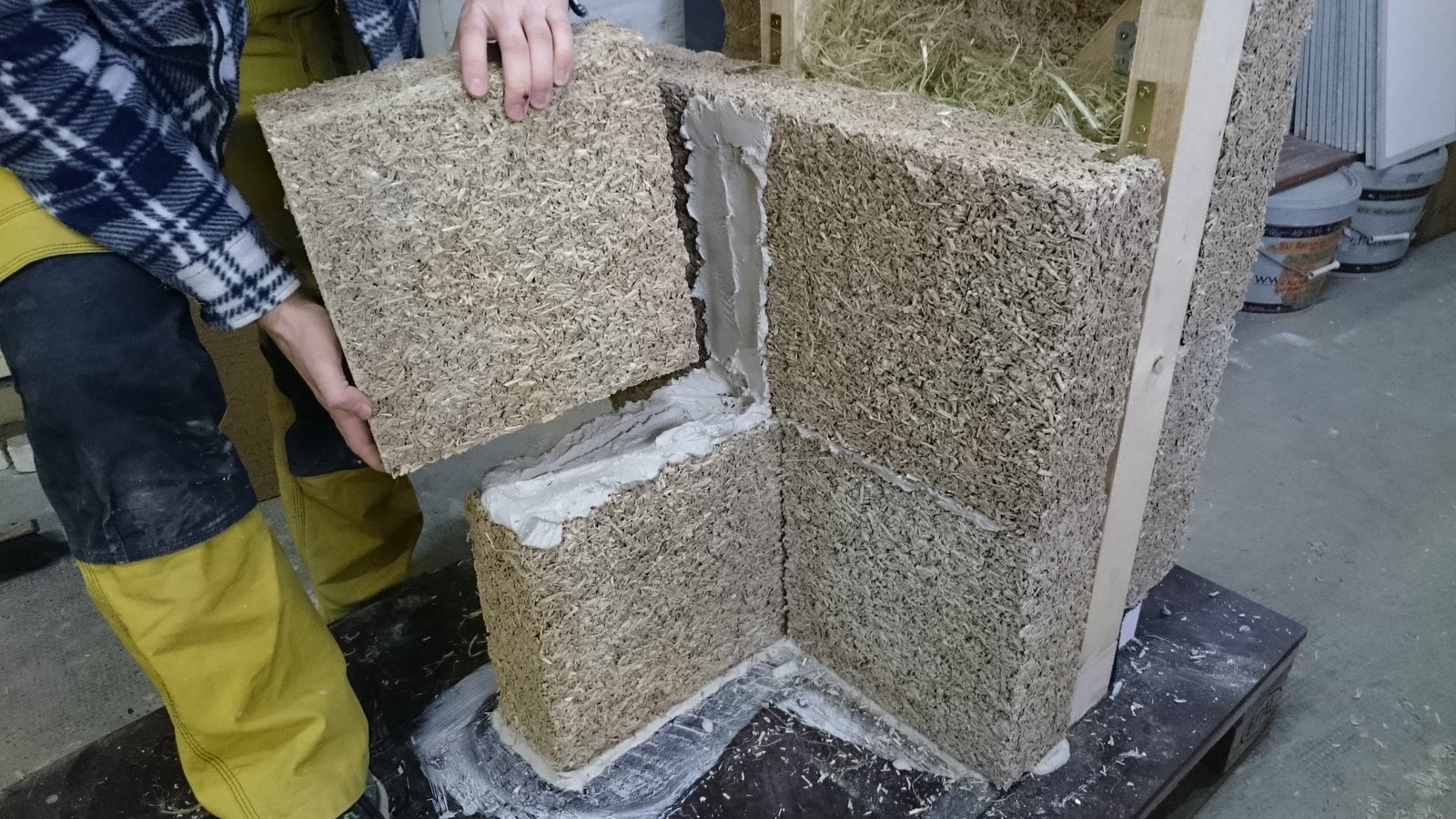 Pose de blocs de chanvre et chaux montés au mortier de chaux contre une ossature en bois