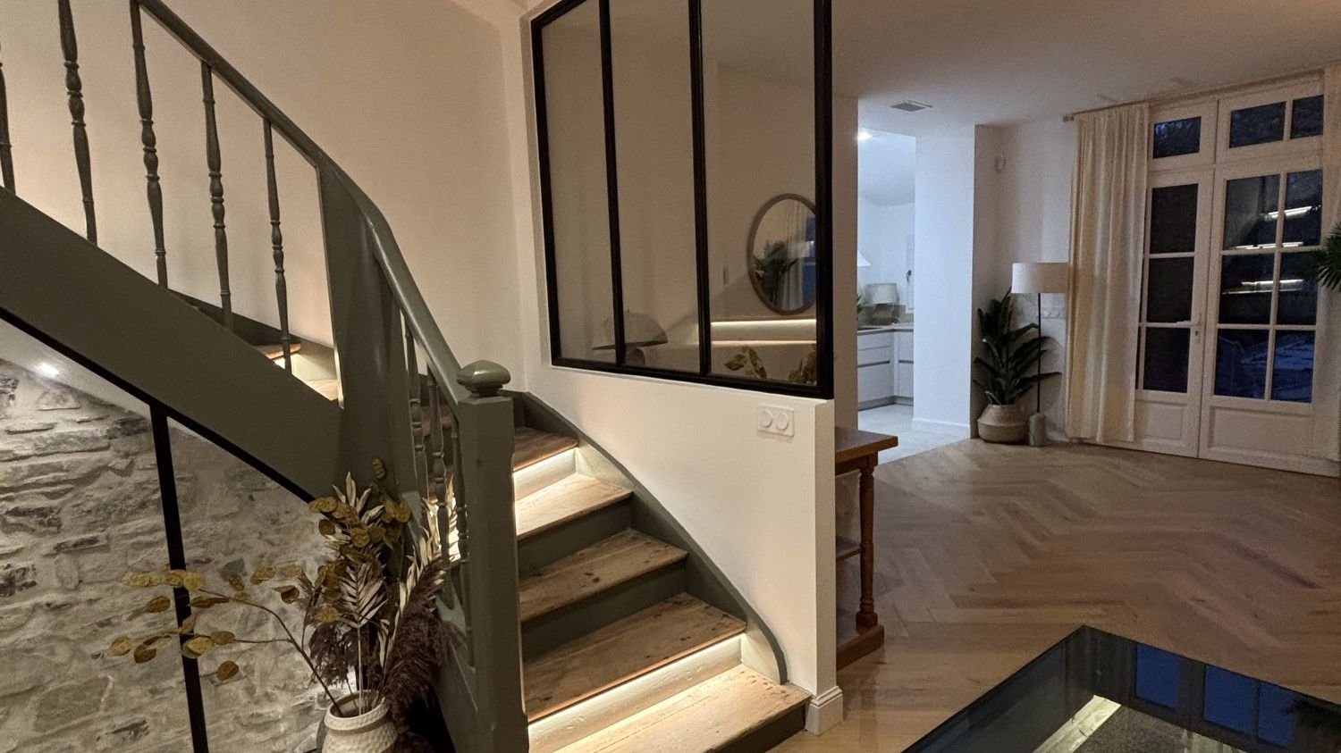 Wooden staircase with a black glass partition and light parquet flooring in a renovated house