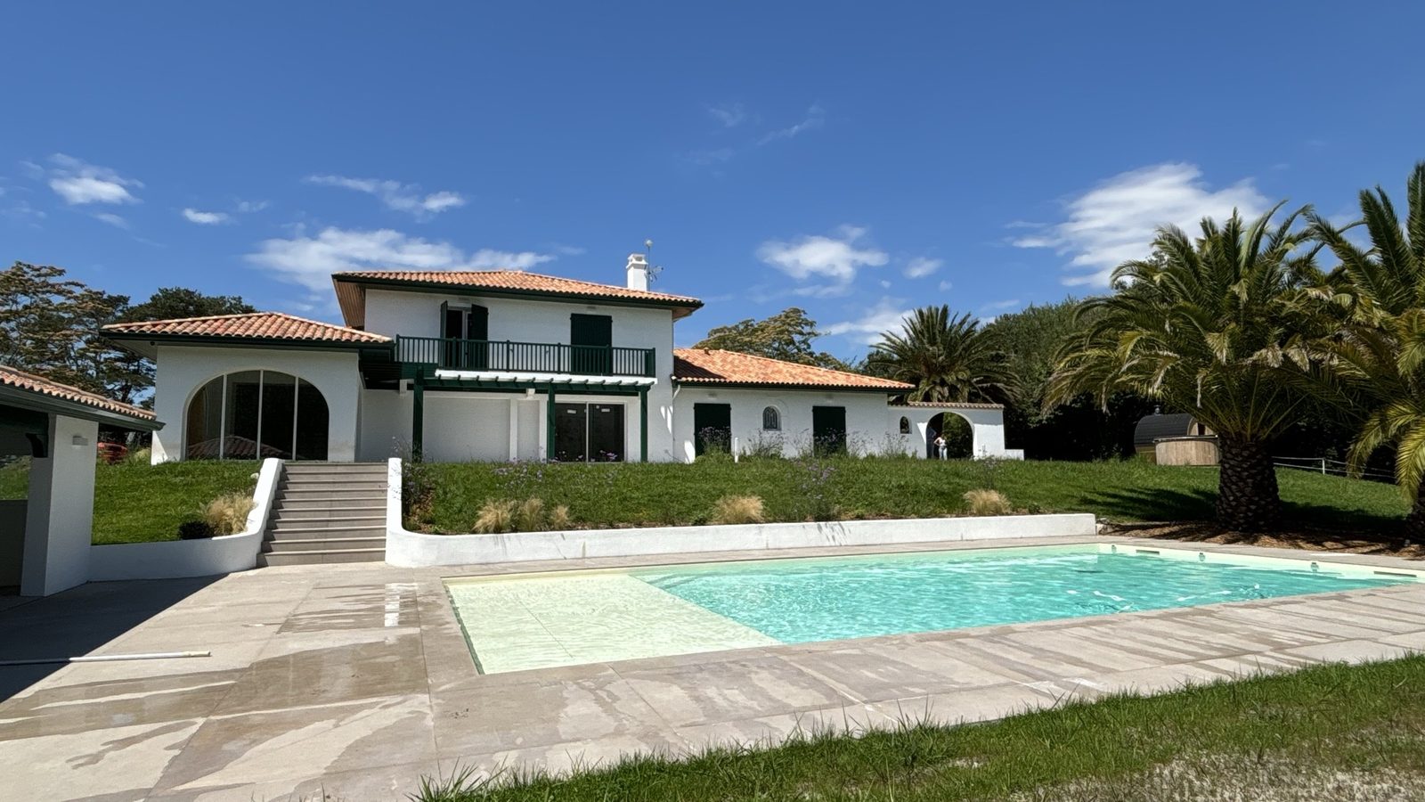 Maison rénovée avec piscine et terrasse en pierre claire, ciel bleu